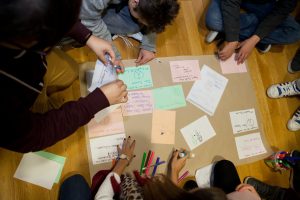 Children gathered at a table, doing a hands-on activity with colored papers and markers.